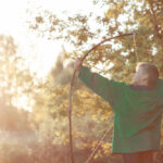 Young,Boy,,Shoot,With,Handmade,Bow,And,Arrow,At,Target