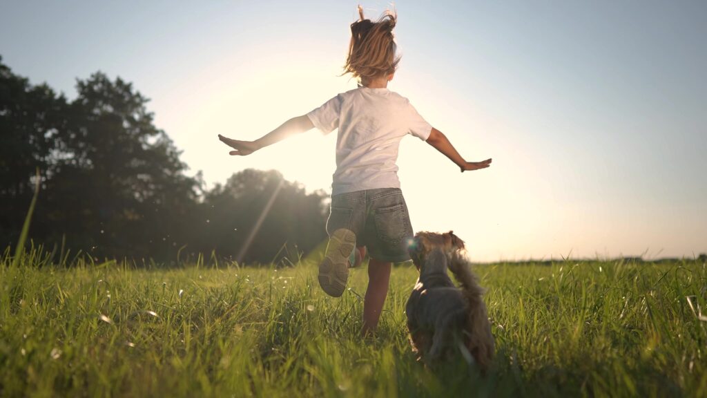 Girl,Running,With,Dog,On,The,Grass,In,The,Park
